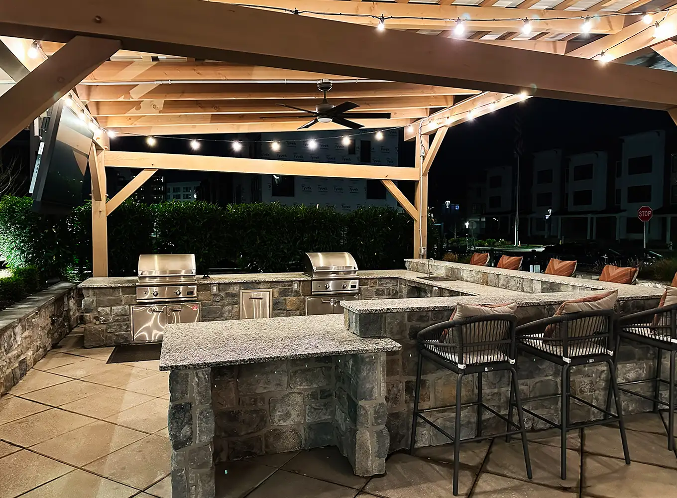 night view of an outdoor kitchen with a pergola